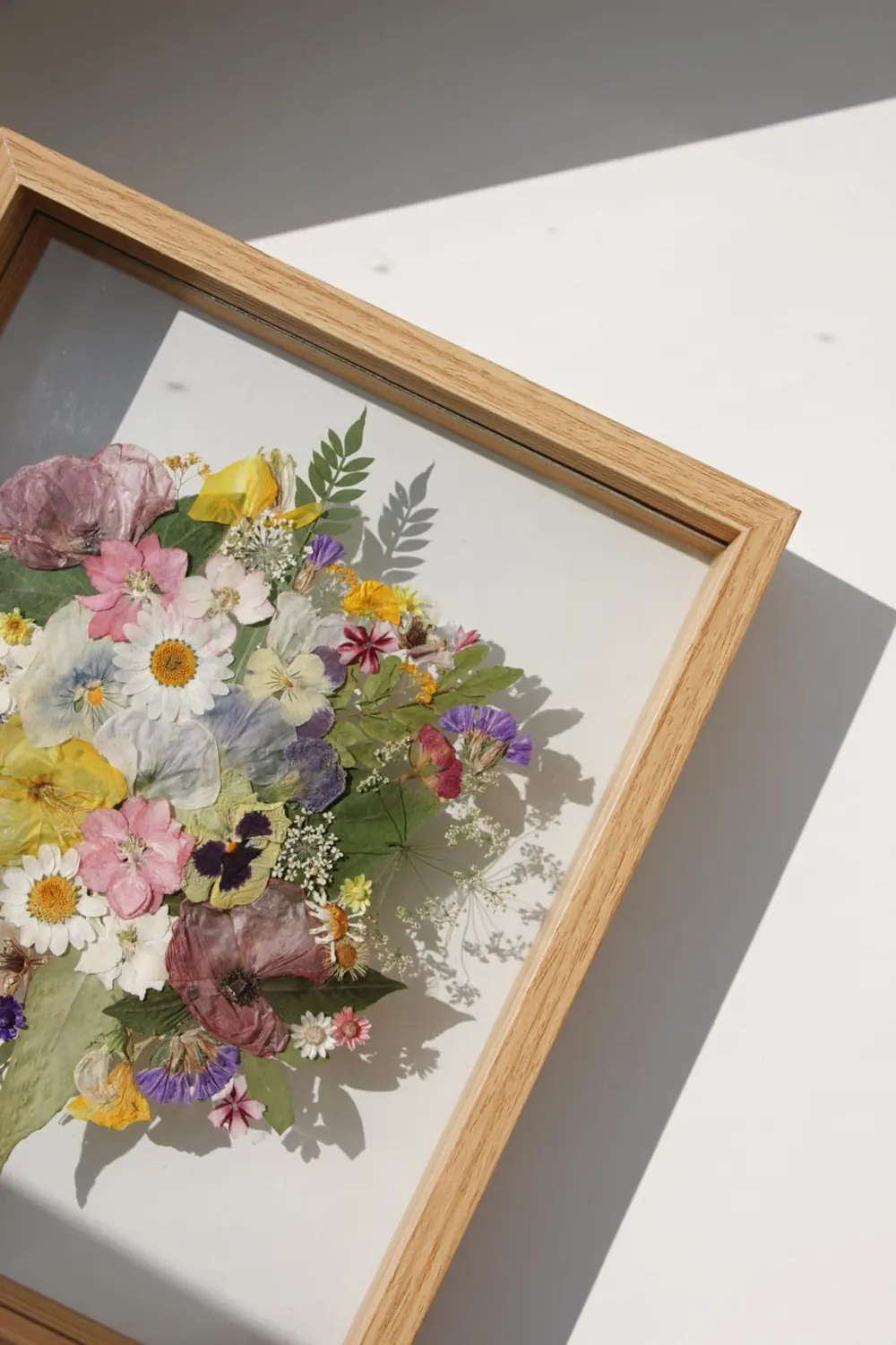 Oak frame corner with a pressed wildflower bouquet under glass